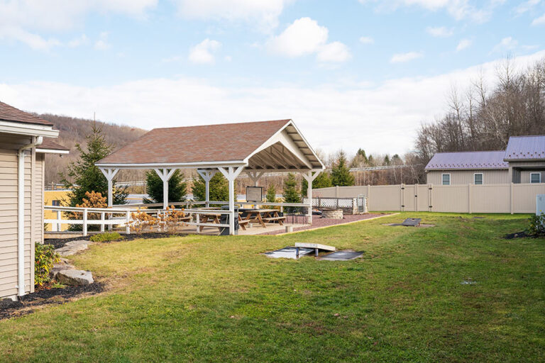 Outdoor pavilion with picnic tables, lawn games, and fire pit area at Silver Pines detox and residential treatment center for addiction and mental health disorders.