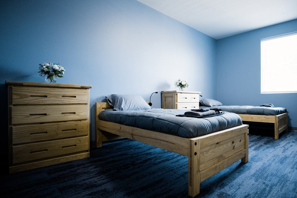 Shared bedroom with two single beds, dressers, and soft blue walls at Silver Pines detox and residential treatment center for addiction and mental health treatment.