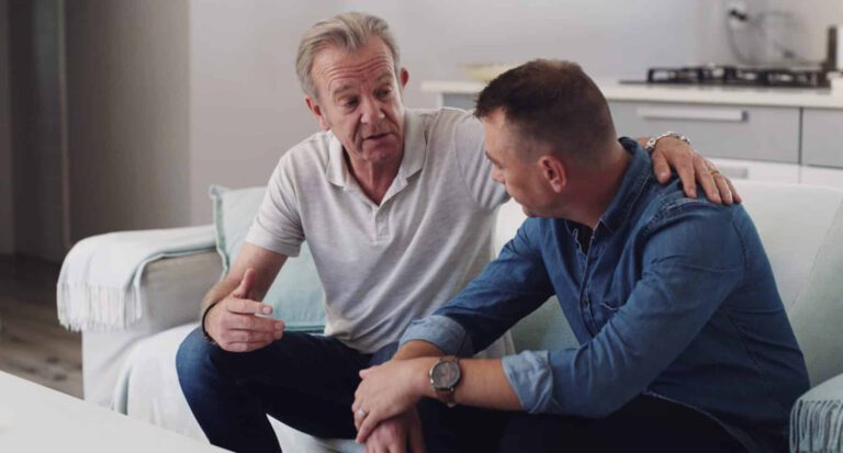 old man and adult son bonding together in living room, conversation and support in home